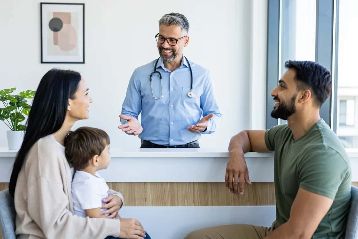 Family doctor welcoming a newcomer family to a BC clinic after they enrolled in MSP health coverage
